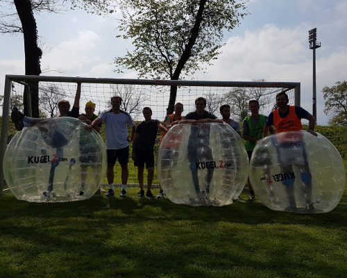 Bubble Soccer Polterabend im freien. Männer stehen in einer Reihe.